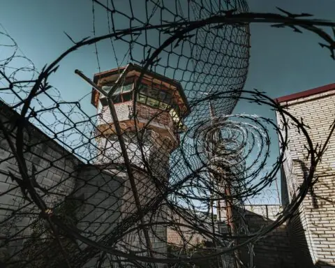 A jail watch tower through barbed wire at a jail.