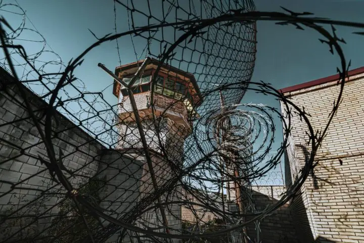 A jail watch tower through barbed wire at a jail.