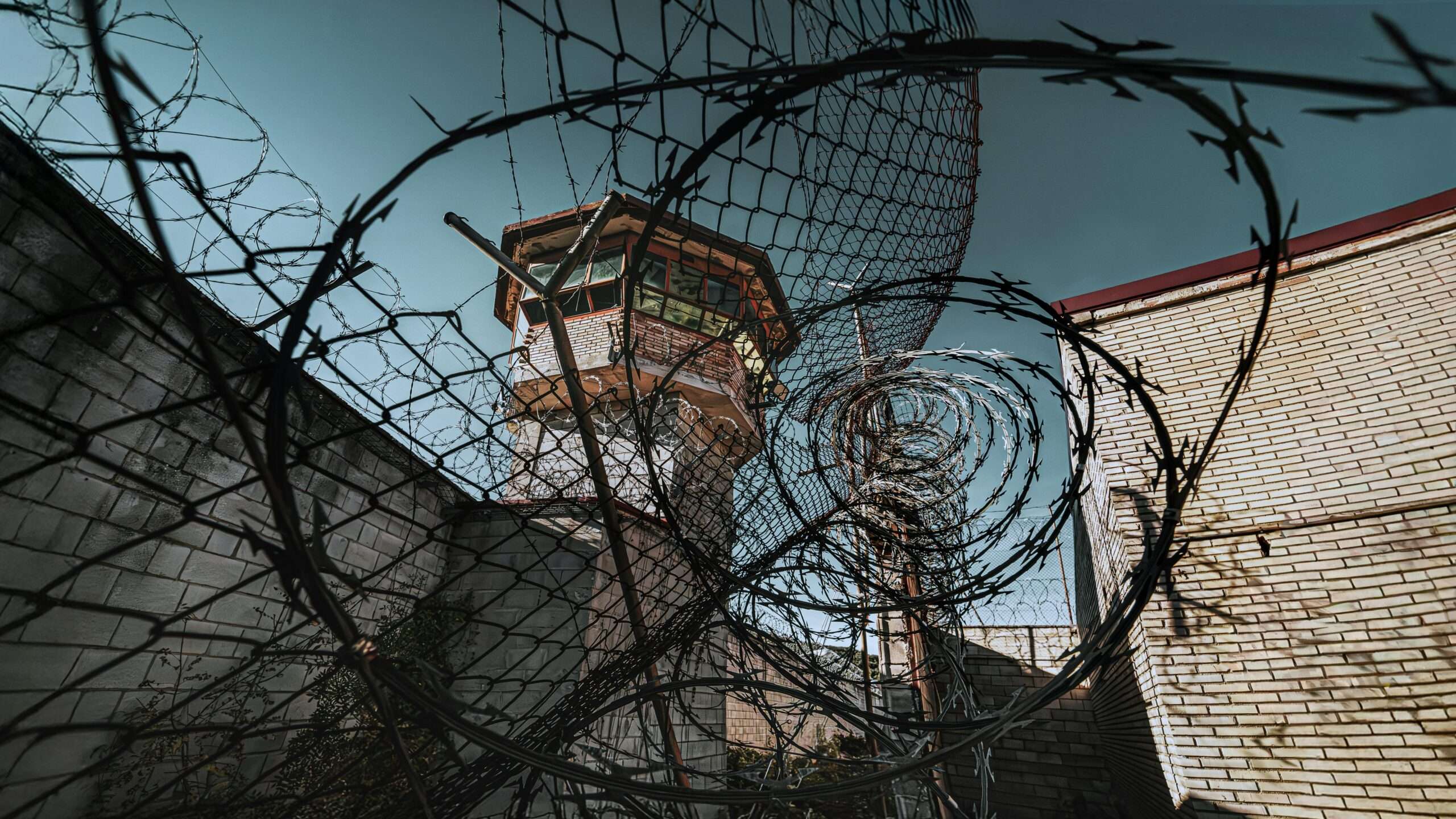 A jail watch tower through barbed wire at a jail.