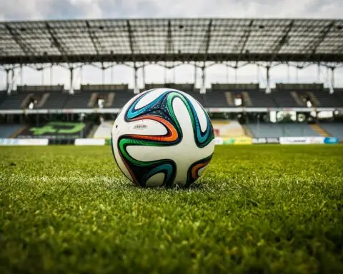 A soccer ball in the middle of the pitch of a stadium.