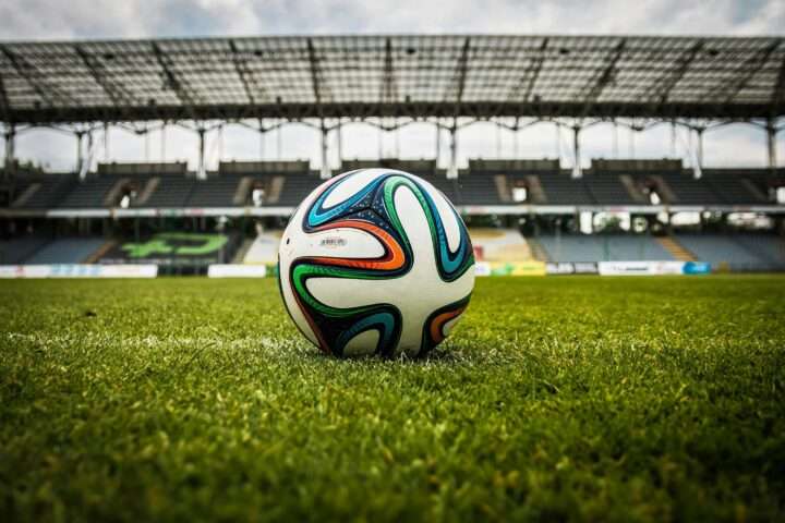 A soccer ball in the middle of the pitch of a stadium.