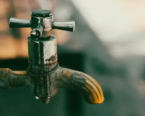 A metal pipe closed before a blurred background.