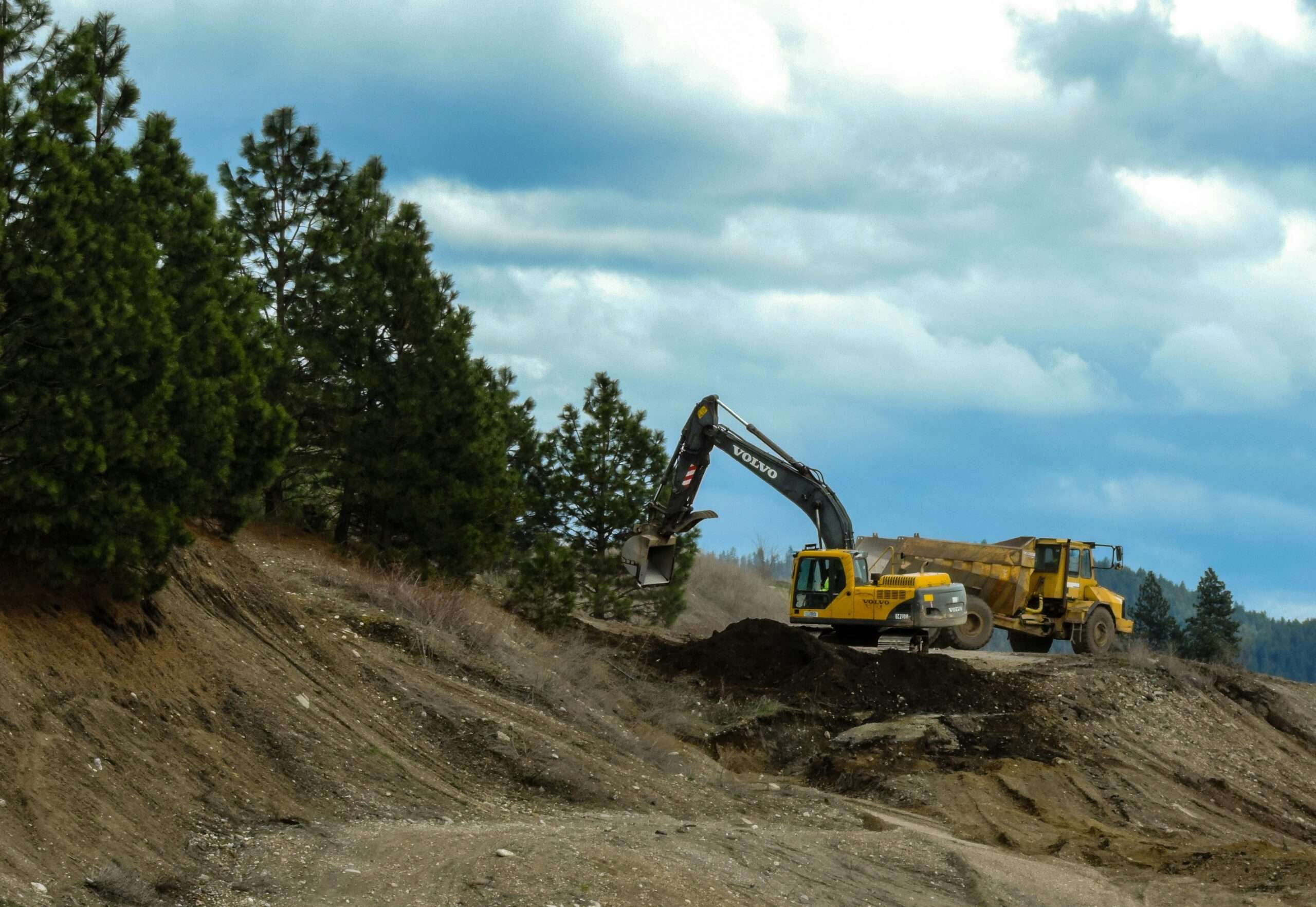 Construction vehicles on a high-elevation mountainside.
