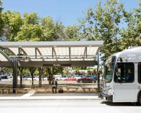 A bus station with a bus picking up a passenger during the day in California.