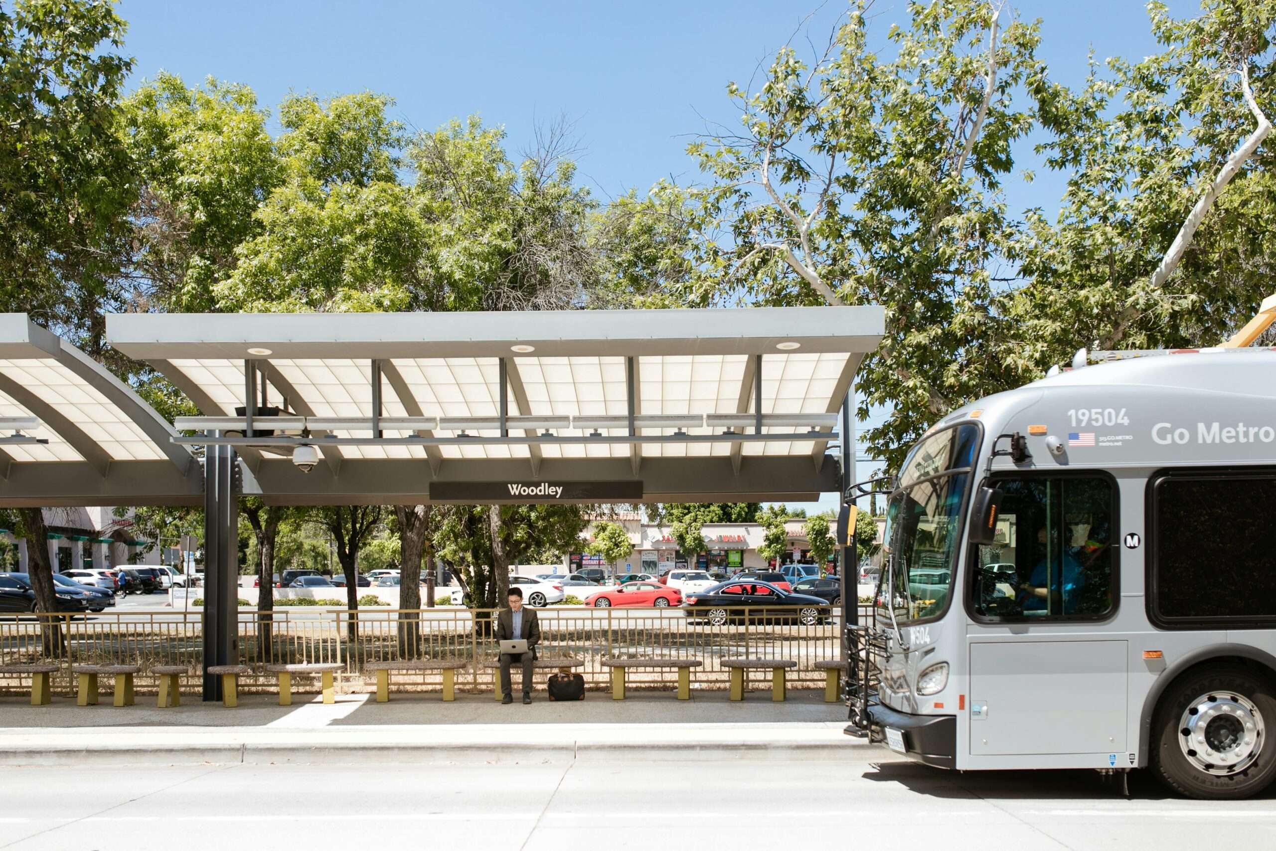 A bus station with a bus picking up a passenger during the day in California.