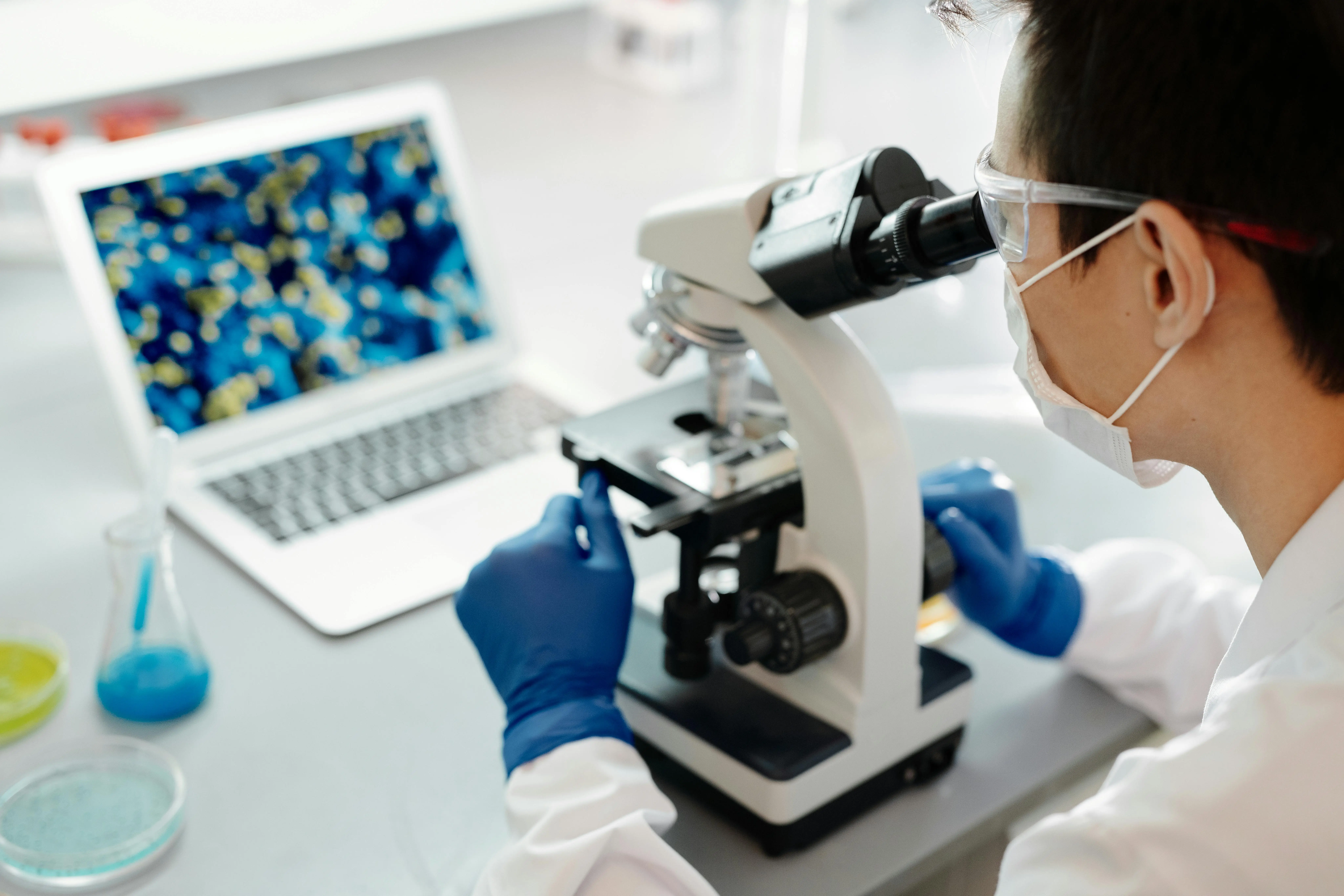 A university researcher looks through a microscope from behind.