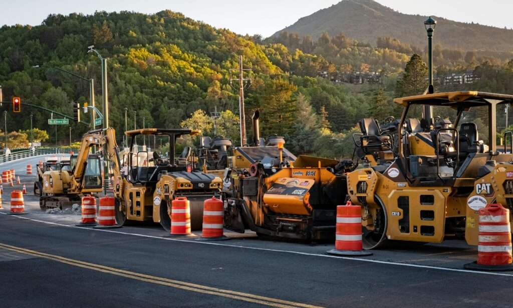 A lineup of construction vehicles alongside a road.