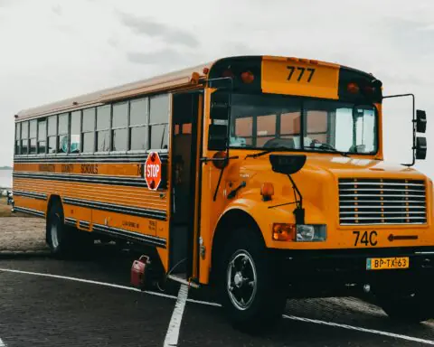 A parked school bus in a parking lot on an overcast day.