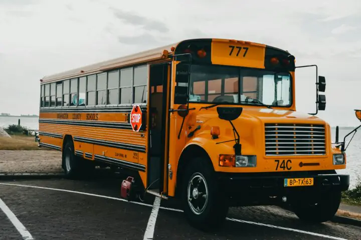 A parked school bus in a parking lot on an overcast day.