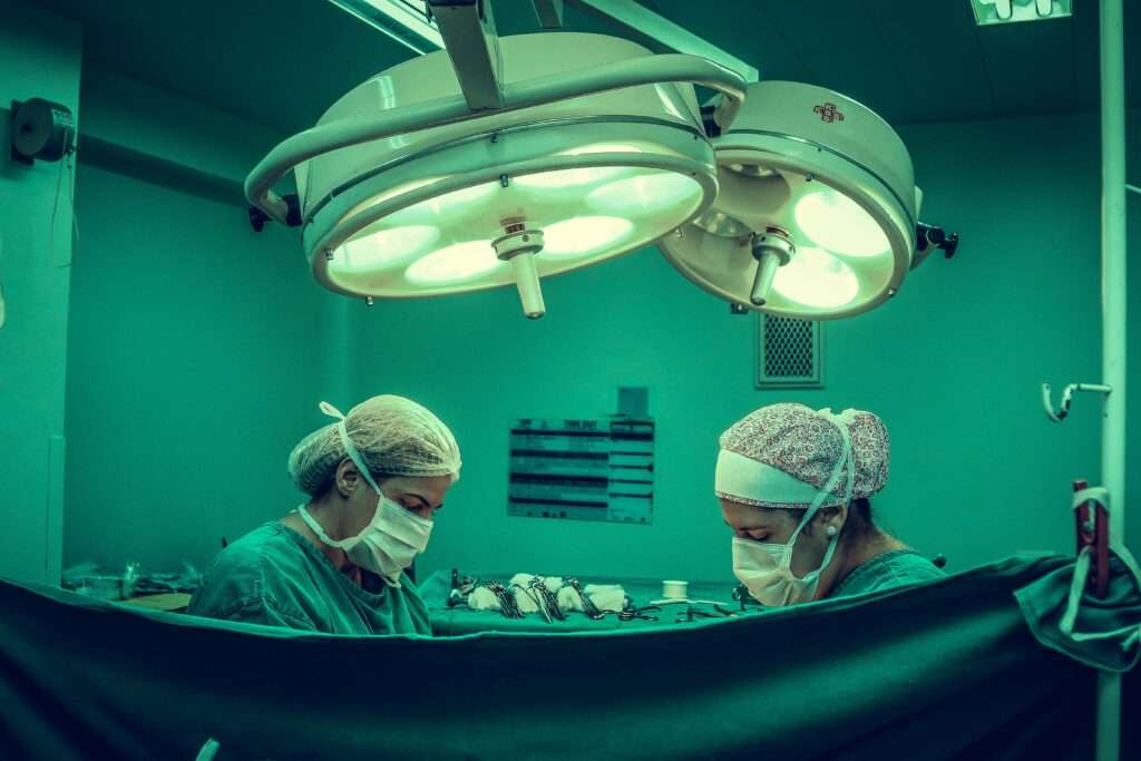Doctors performing surgery below a surgical light.