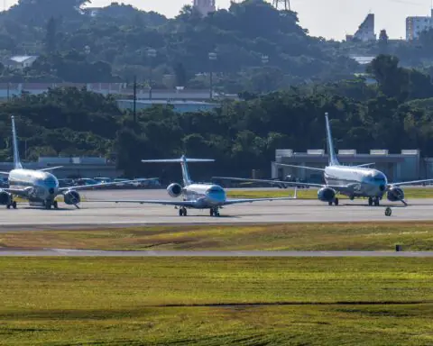 Three airplanes at a taxiway at an airport from a distance.