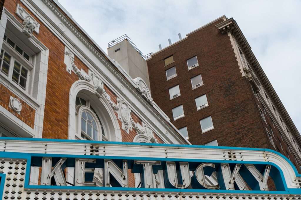 City buildings in Kentucky with a lit Kentucky sign above a theater.