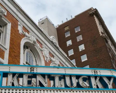 City buildings in Kentucky with a lit Kentucky sign above a theater.