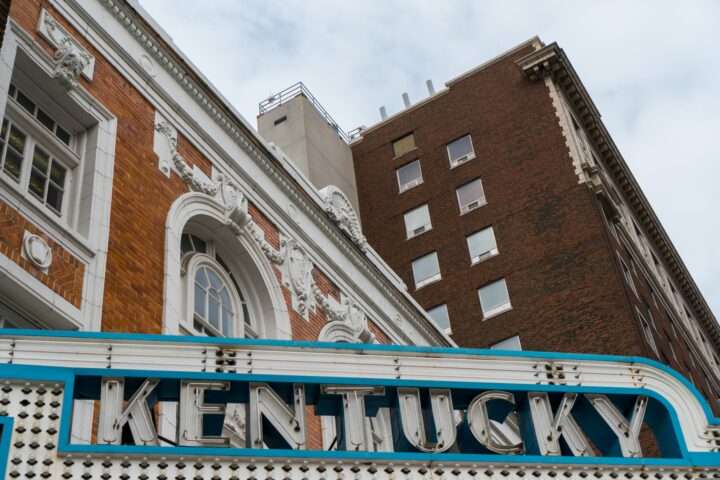 City buildings in Kentucky with a lit Kentucky sign above a theater.