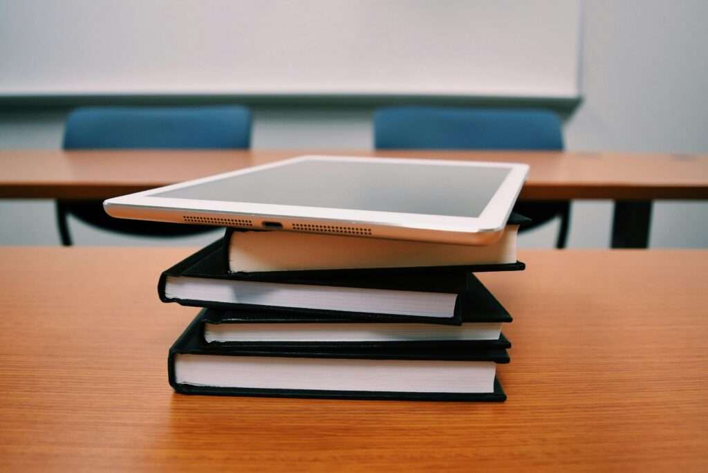 Textbooks and school technology on a desk in a classroom at an academic facility.