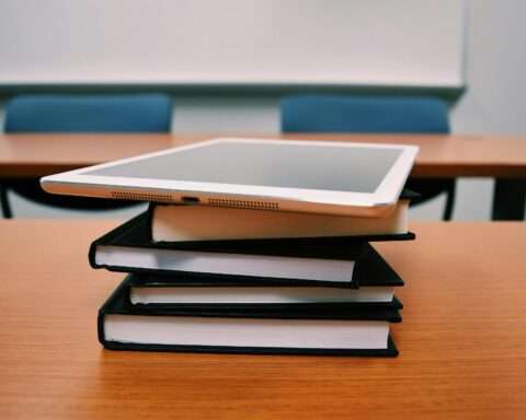 Textbooks and school technology on a desk in a classroom at an academic facility.