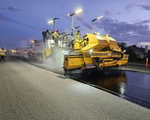 A road paving machine working on a road during the nighttime.