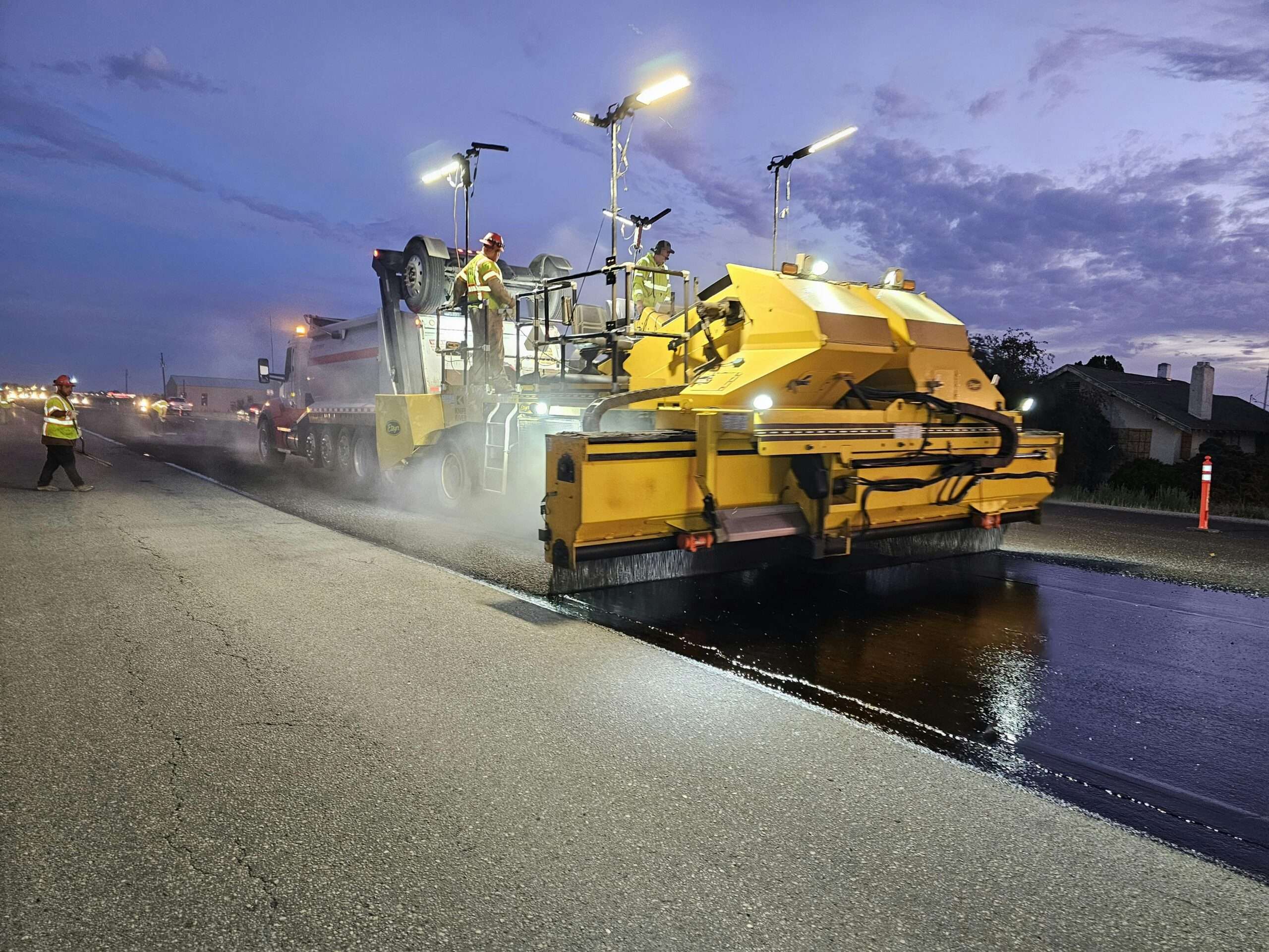 A road paving machine working on a road during the nighttime.