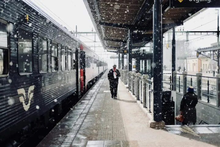 A person walking along a train station with a train awaiting passengers.