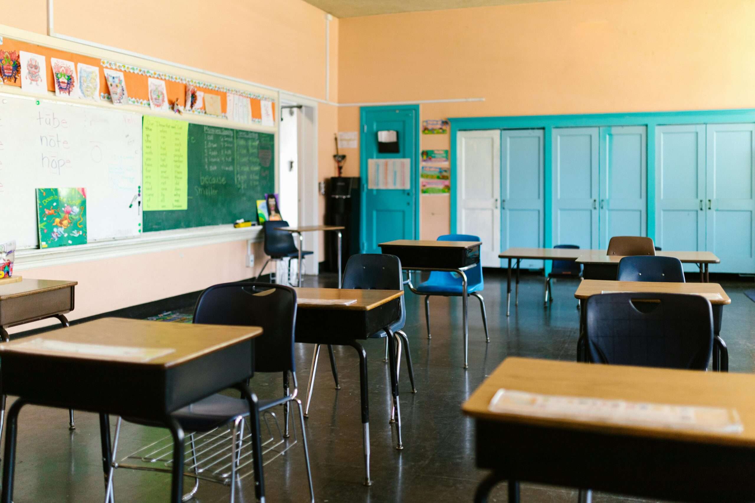 A person less school classroom with desks, wall decor and chairs.