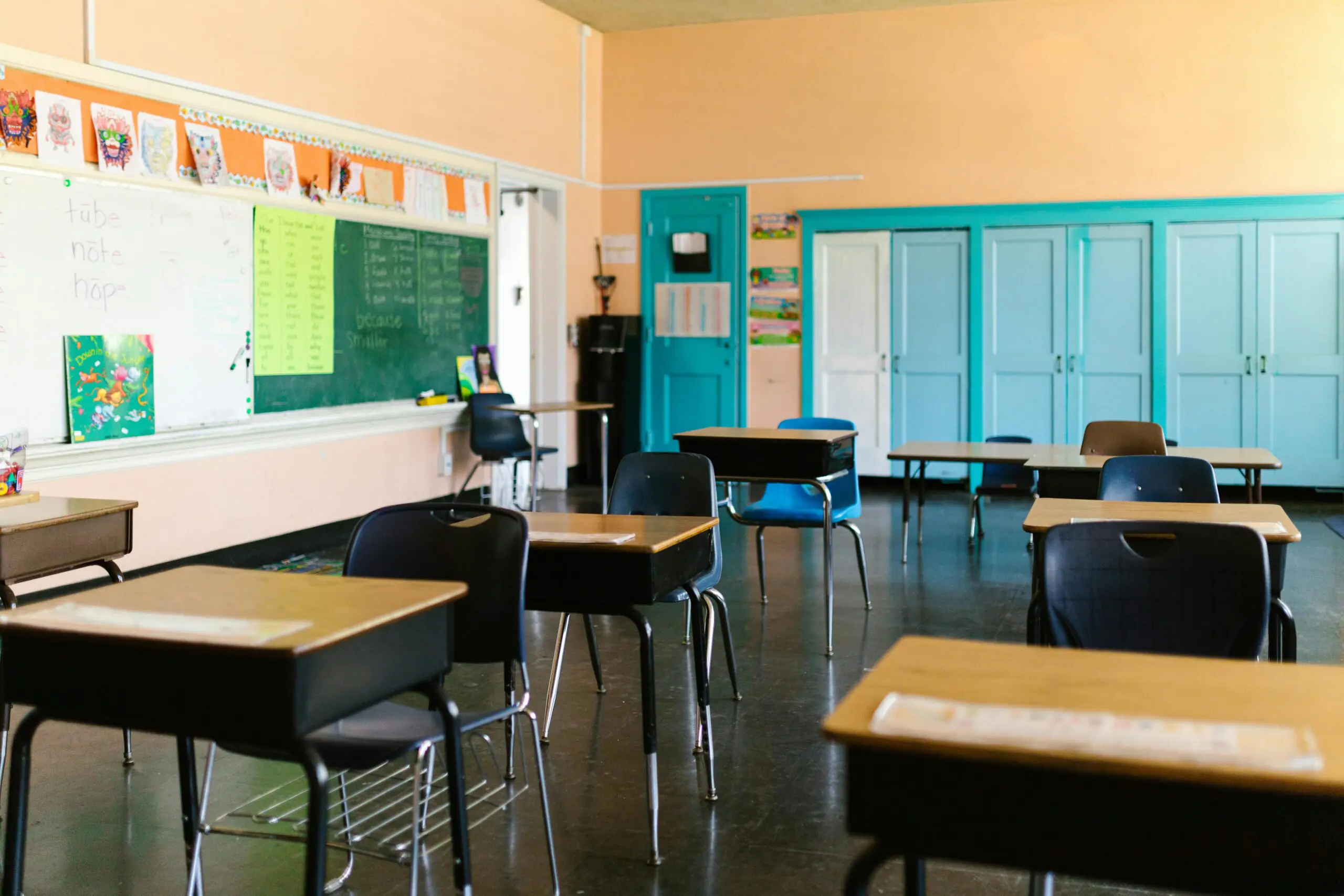 A person less school classroom with desks, wall decor and chairs.