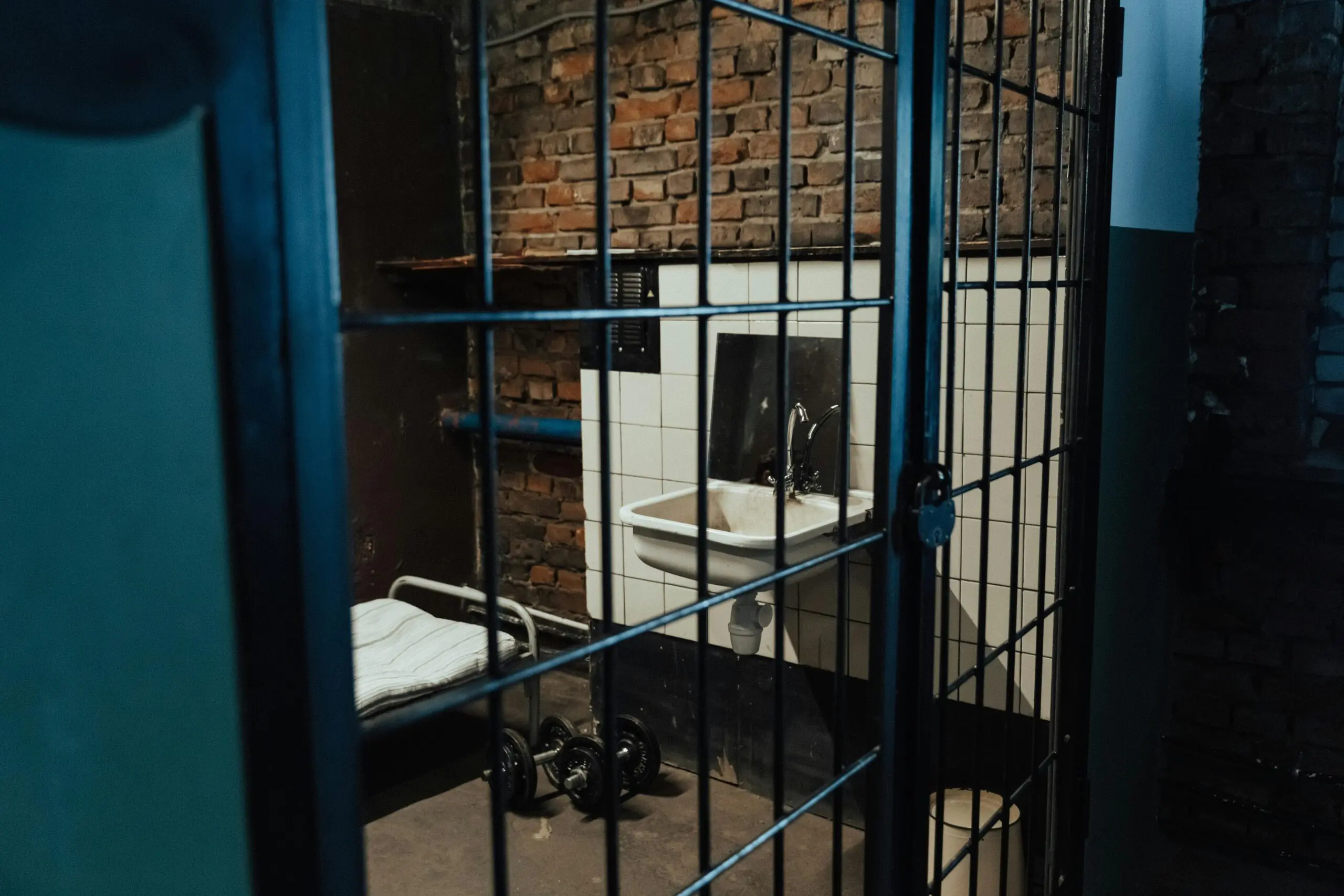 A jail room in a detention center with a sink, dumbells and a bed.