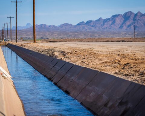 An agricultural water conveyance system in a field before distant mountains.