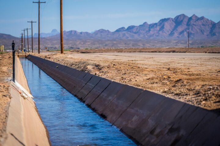An agricultural water conveyance system in a field before distant mountains.