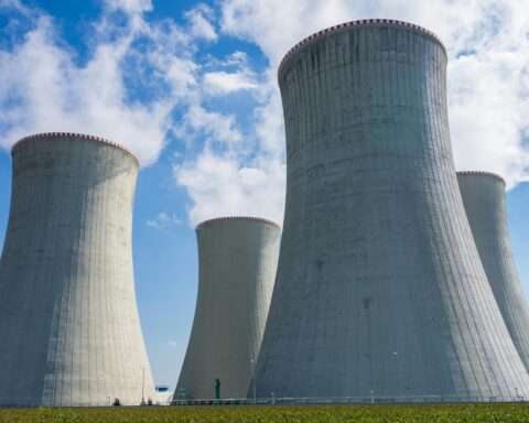 Four nuclear cooling towers before a cloudy blue sky.