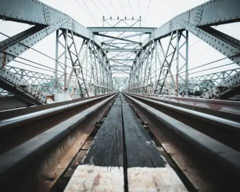A ground up view of a rail-carrying bridge on a sunny day.