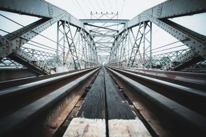 A ground up view of a rail-carrying bridge on a sunny day.