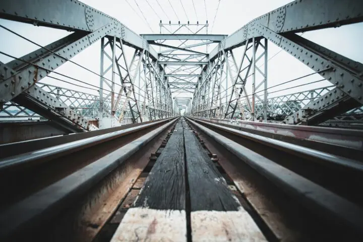 A ground up view of a rail-carrying bridge on a sunny day.