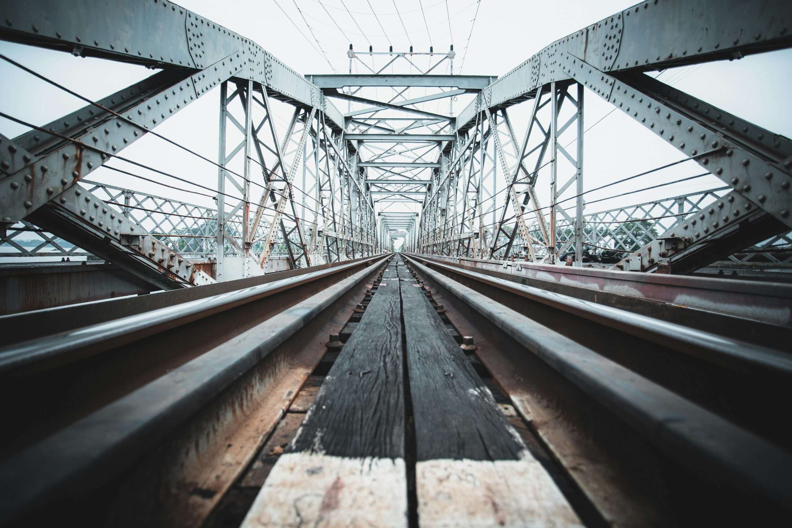 A ground up view of a rail-carrying bridge on a sunny day.
