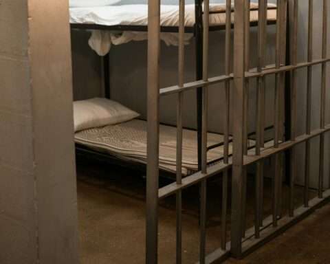 The interior of a jail cell with a bunk bed and two dumbbells.