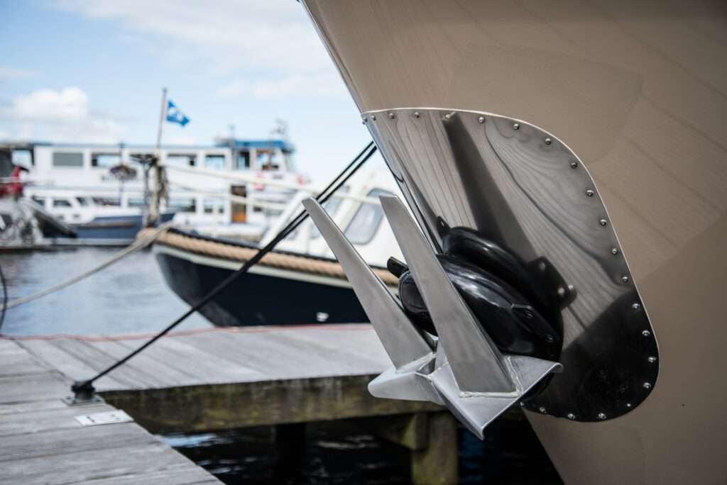 An anchored attached to a small ship at a shipyard on a sunny day before a second small vessel.