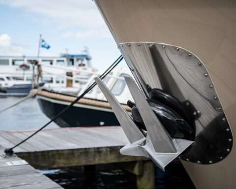 An anchored attached to a small ship at a shipyard on a sunny day before a second small vessel.