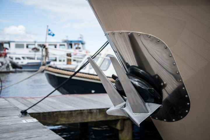 An anchored attached to a small ship at a shipyard on a sunny day before a second small vessel.