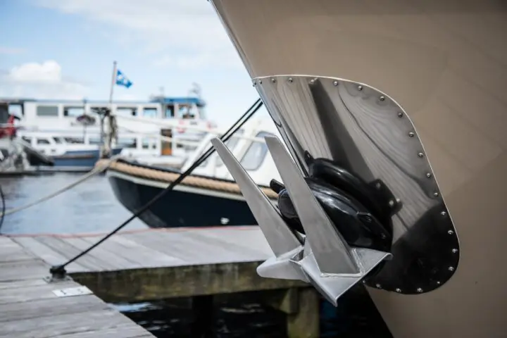 An anchored attached to a small ship at a shipyard on a sunny day before a second small vessel.