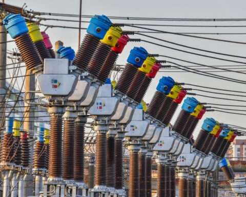 A series of electric transformers before a grey sky.