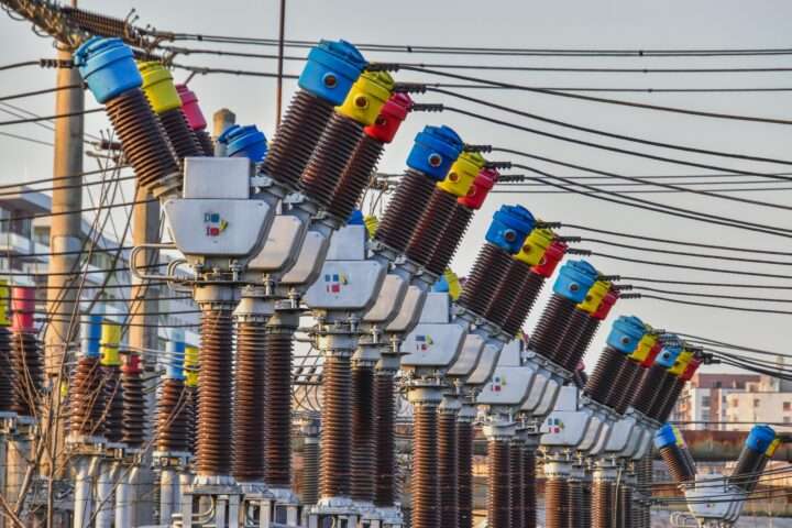 A series of electric transformers before a grey sky.