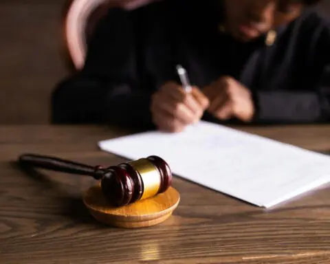 A gavel and paper before a judge in a courthouse.