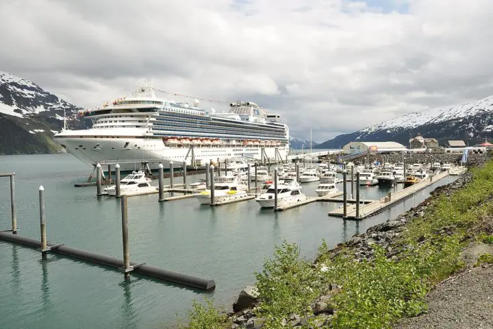 A cruise ship at port in Alaska near other ships and before a cloudy sky.