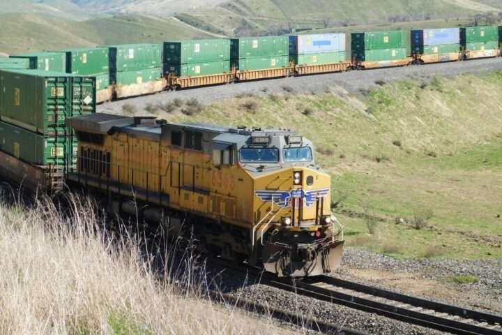 A freight locomotive on a railroad track in a grassy field.