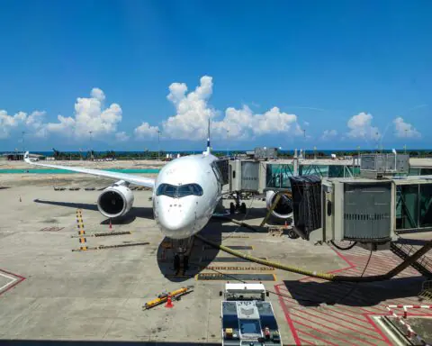 An airplane at a gate at an airport on a sunny day.