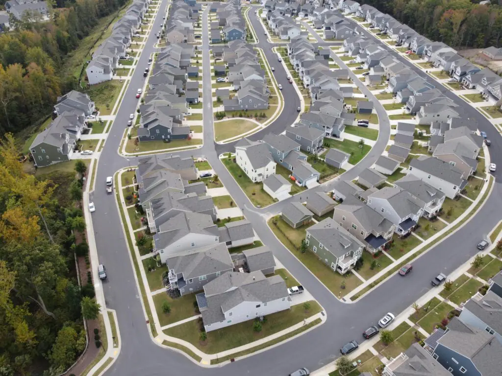 An aerial image of a housing development around trees and roads.