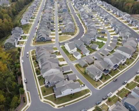 An aerial image of a housing development around trees and roads.
