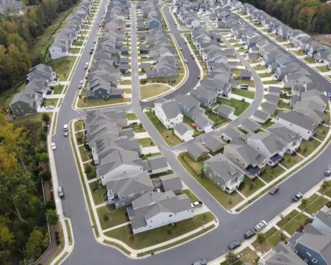 An aerial image of a housing development around trees and roads.