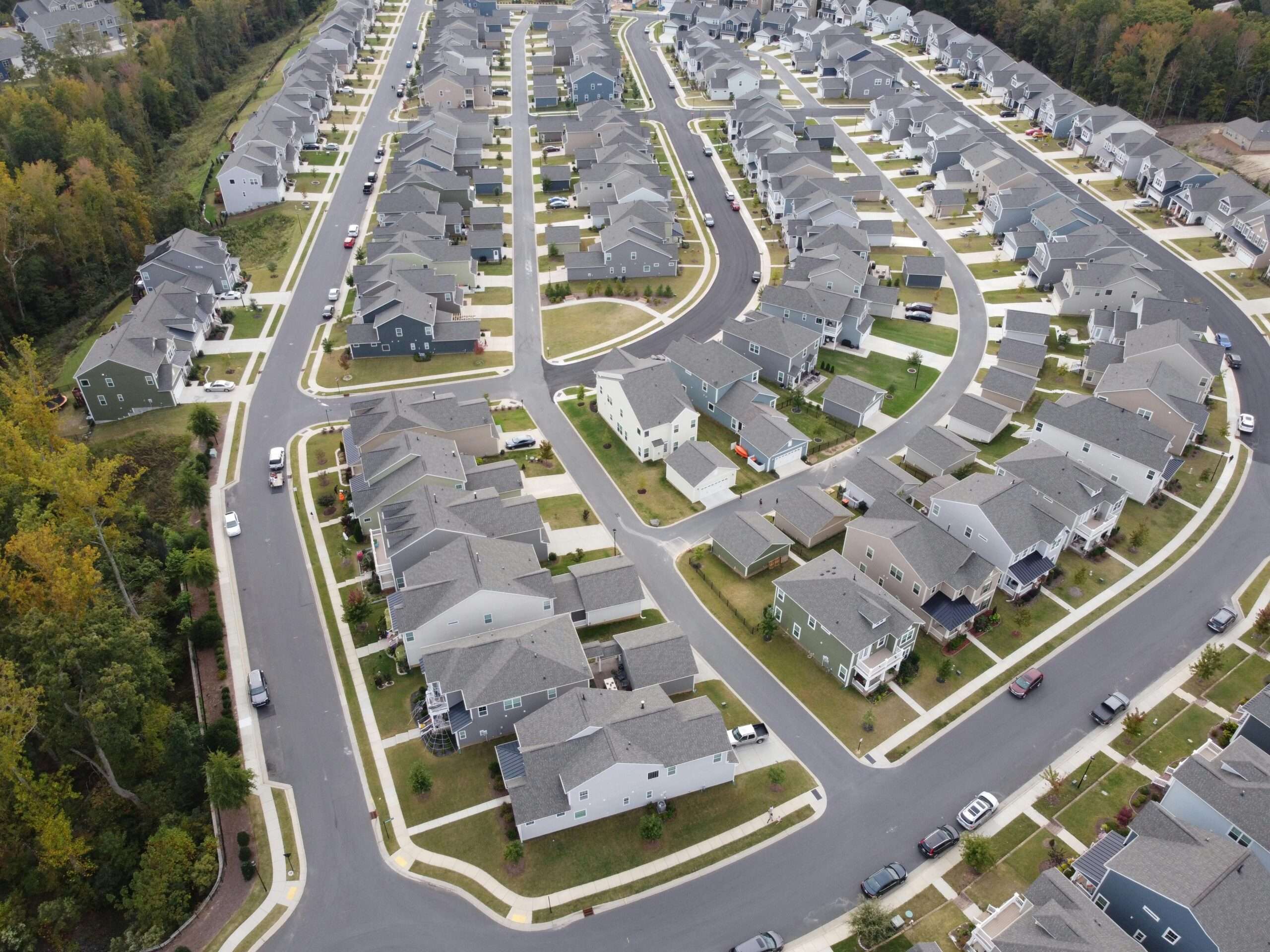 An aerial image of a housing development around trees and roads.