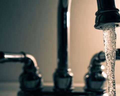 A faucet in the dark pouring water into a sink.