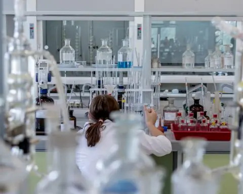 A lab researcher manages beakers and other tools in a lab.
